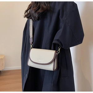 Détail du sac à bandoulière en cuir blanc cassé avec une large sangle vintage à motifs