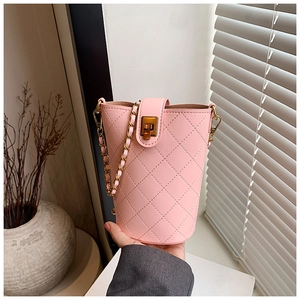 Detailed macro of pink quilted bucket bag showing gold twist-lock and metal chain strap