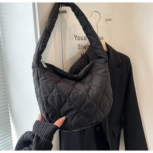 Detail of black quilted nylon tote bag with heart-shaped texture and silver zipper closure