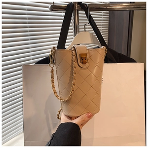 Detailed close-up of quilted beige bucket bag with gold chain strap and metal snap closure