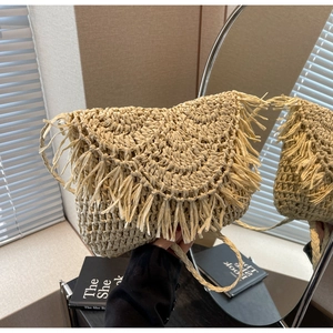 Detail of bohemian straw shoulder bag featuring textured fringe and woven fiber strap