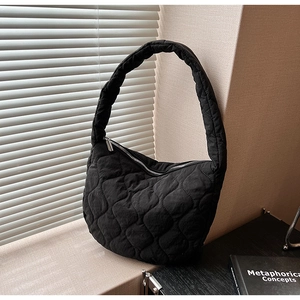 Detail of black quilted nylon tote bag with crescent shape and smooth zipper closure