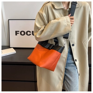 Detail of orange nylon bucket bag with black bow decoration and wide adjustable strap