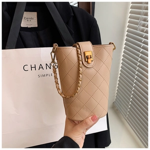 Close-up of beige quilted bucket bag with gold chain strap and metal lock detail