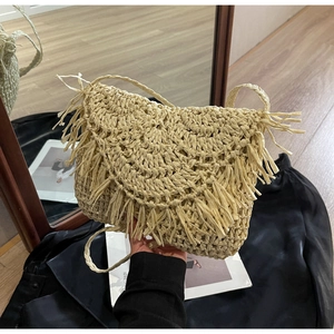 Close-up of the beige straw shoulder bag featuring fringe trim and a woven flap cover
