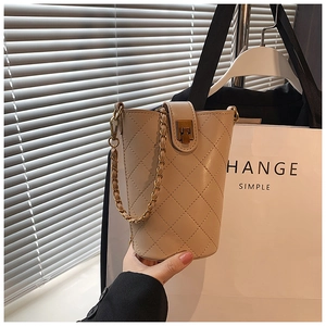 Detail of beige quilted bucket bag showing leather chain strap and metallic twist lock