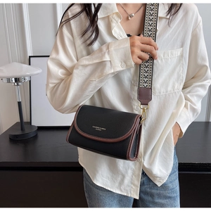 Détail du sac bandoulière en cuir noir avec sangle tissée géométrique et boucles dorées