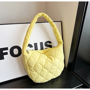 Close-up of yellow quilted nylon cloud bag with diamond stitching and silver zipper detail