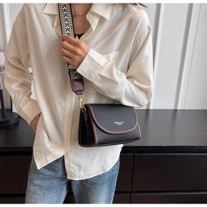 Détail du sac bandoulière en cuir grainé noir avec bordure marron et sangle tissée