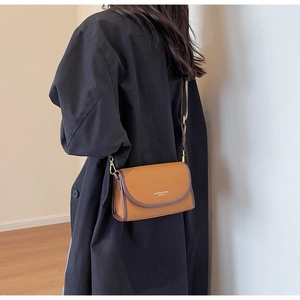 Détail du sac bandoulière en cuir marron à motif litchi avec boucle dorée réglable
