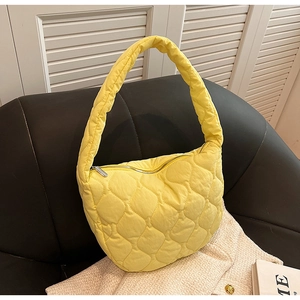 Detail of yellow quilted nylon tote bag showing cloud-like texture on a leather chair