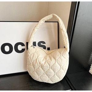 Close-up of cream quilted nylon tote bag with soft diamond texture and zip closure