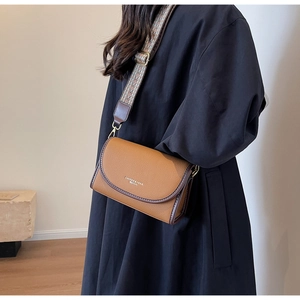 Détail du sac en cuir marron avec une large bandoulière en jacquard au style vintage