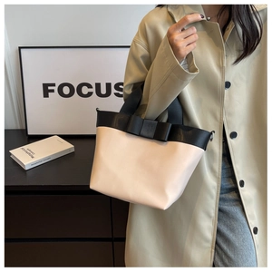Detail of contrast bow tote bag in beige and black with metal strap hooks
