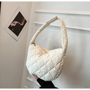 Close-up of cream quilted nylon tote bag with gourd stitching and silver zipper detail