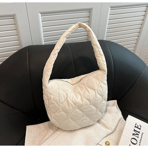 Close-up of quilted crescent shoulder bag on leather seat with a minimalist magazine
