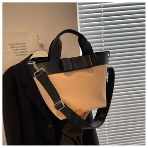 Detail of a beige nylon bucket bag featuring a large black bow and adjustable wide strap