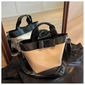 Detail of contrast stitch nylon bucket bag with a large bow and adjustable strap