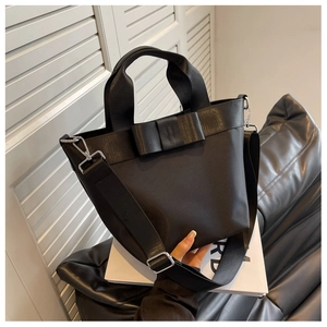 Close-up of a black nylon bucket bag with a decorative bow and silver hardware detail