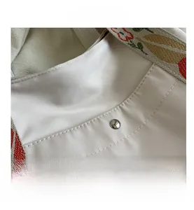 Close-up of beige nylon tote bag with floral strap and secure silver magnetic clasp