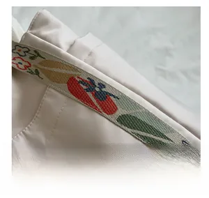Detail view of cream nylon tote bag featuring exquisite colorful floral embroidery on wide strap