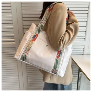 Detail of the white nylon tote bag showing floral jacquard straps and side pocket