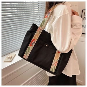 Close-up of black nylon tote bag with colorful vintage floral embroidery shoulder strap