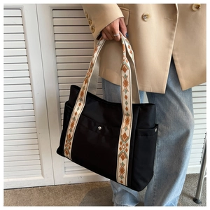 Detail of black nylon tote bag featuring ethnic geometric patterns on wide shoulder straps