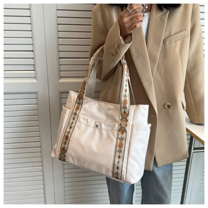 Macro detail of white nylon tote bag with colorful geometric woven shoulder strap