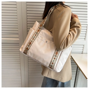 Detail view of large white nylon tote bag with ethnic geometric woven shoulder strap