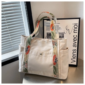 Detail of nylon tote bag with floral woven strap and metal snap front pocket