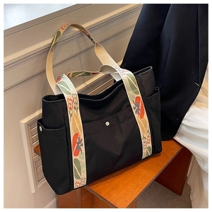 Detail of black nylon tote bag with floral pattern wide strap and front metal snap pocket