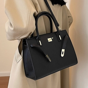Classic black leather handbag with gold hardware worn with a stylish khaki trench coat