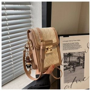 Detail der beigen Stepptasche mit Metallverschluss und süßem Bullen-Anhänger