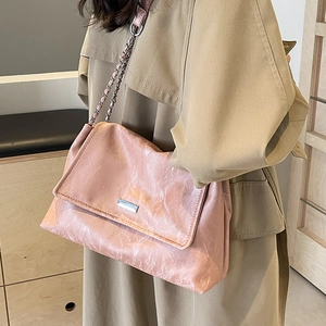 Pink pleated leather tote bag with silver chain strap shown worn with a trench coat