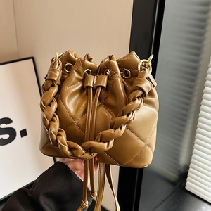Brown quilted leather bucket bag with woven handle and drawstring closure shown in use