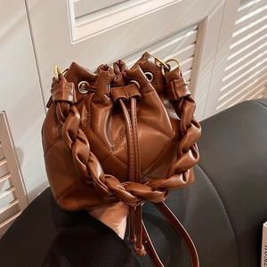 Brown quilted bucket bag with woven handle and gold hardware shown in a lifestyle shot