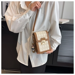 Nahaufnahme cremefarbene Stepptasche mit goldenem Verschluss und Kuh-Anhänger