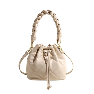 Chic quilted bucket bag in beige PU leather with a thick woven handle and shoulder strap