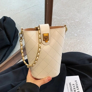 Quilted cream bucket bag with gold chain strap and metal lock in minimalist style