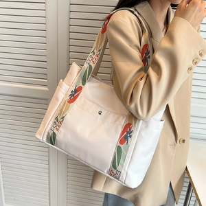 Large beige nylon tote bag with floral jacquard strap shown on a shoulder