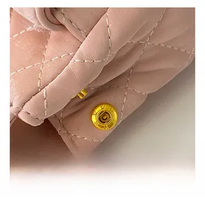 Détail du bouton pression magnétique doré sur un sac bandoulière rose matelassé