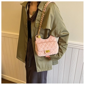 Détail du sac bandoulière rose matelassé en velours avec charme fleuri doré et chaîne