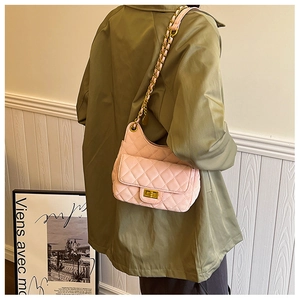 Détail du sac selle matelassé rose avec fermoir doré et bandoulière en chaîne