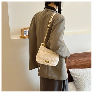 Détail du sac à main matelassé blanc avec fermoir doré et bandoulière chaîne sur modèle