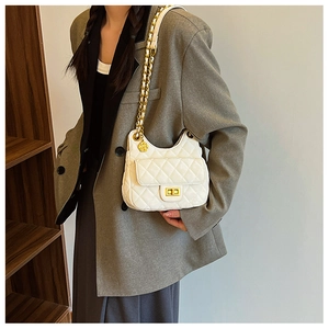 Détail de la texture cuir matelassé blanc et fermoir doré sur le sac bandoulière