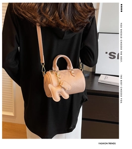 Detail der apricot-rosa Zylindertasche aus Leder mit Bärenanhänger am Modell