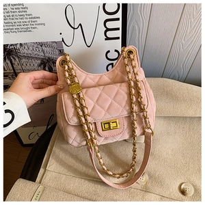 Détail du sac selle rose matelassé avec breloque camélia dorée et bandoulière