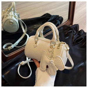 Nahaufnahme weiße Zylindertasche aus strukturiertem Leder mit goldenen Details