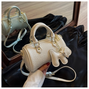 Detailaufnahme der weißen Zylindertasche mit Lederstruktur und goldener Hardware